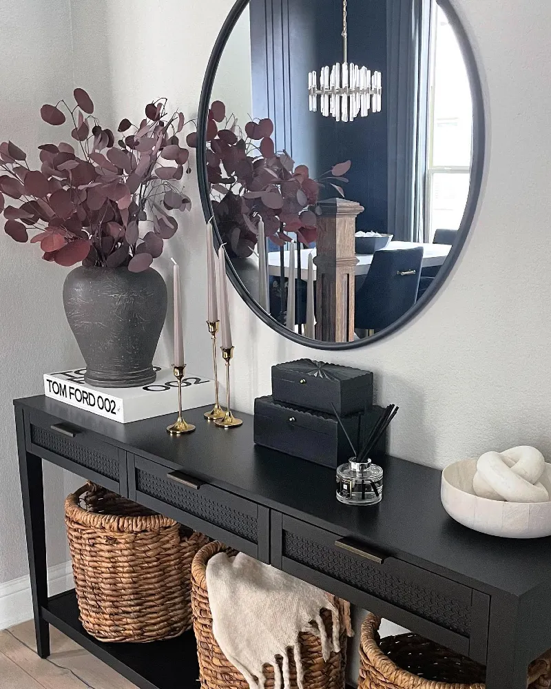10. Black Console Table with Round Mirror, Plum Stems, and Woven Baskets