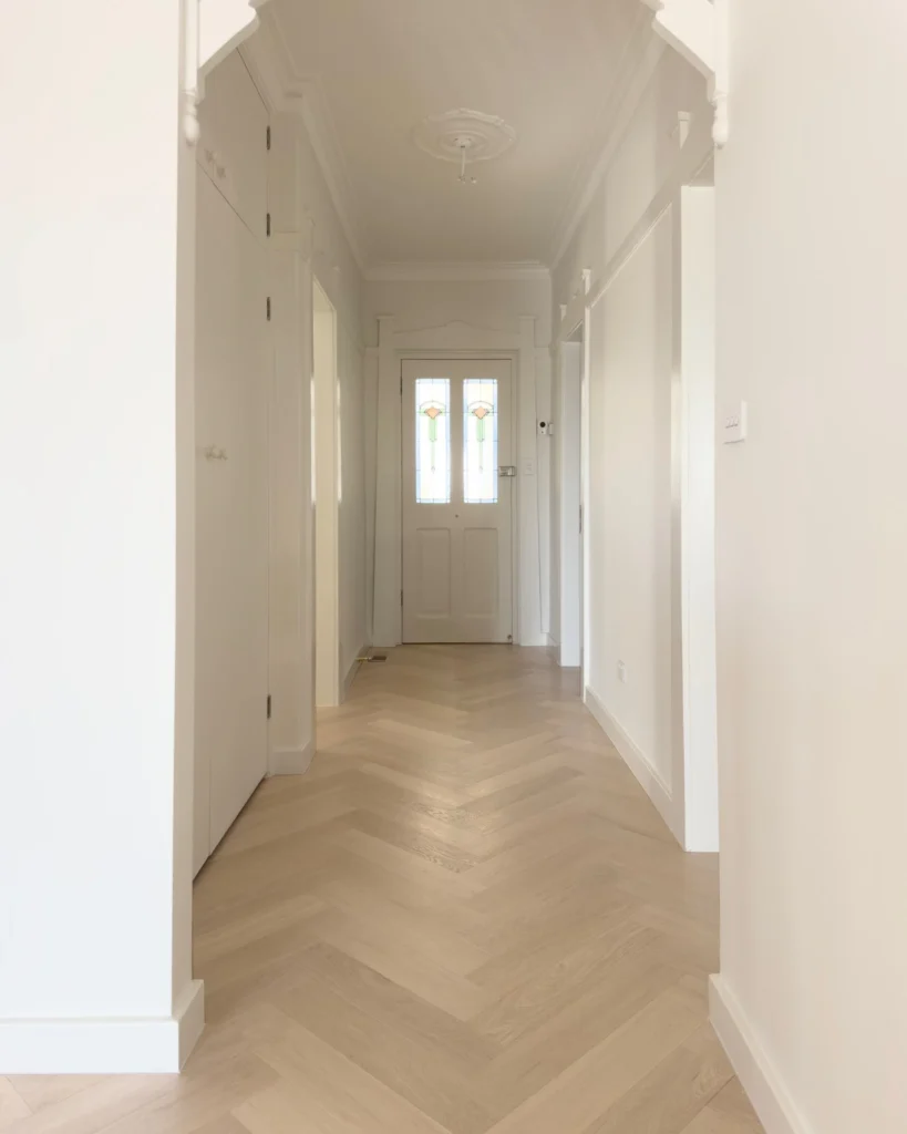 10. Pale Oak Herringbone Hallway with White Trim and Soft Glass Door Light
