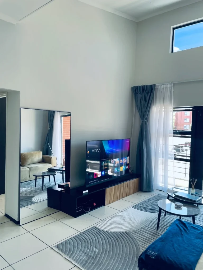 10. Tall Living Room Wall with Leaning Mirror, Low TV Console, and Curved Gray Rug