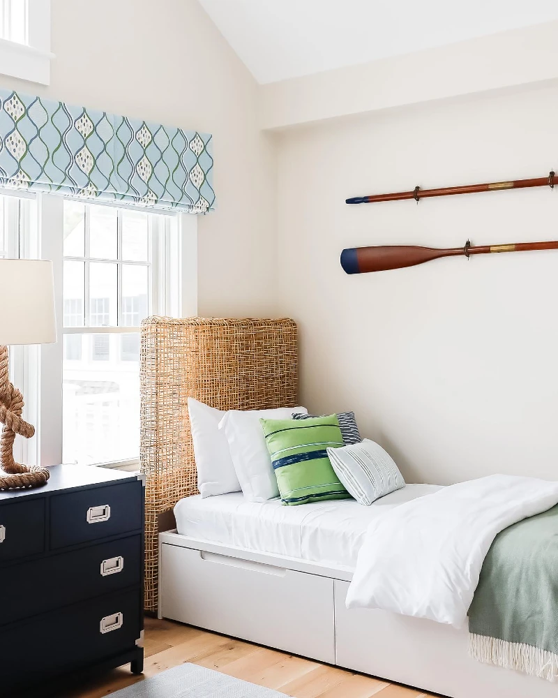 10. White Storage Daybed with Wicker Headboard, Navy Dresser, and Oar Wall Decor
