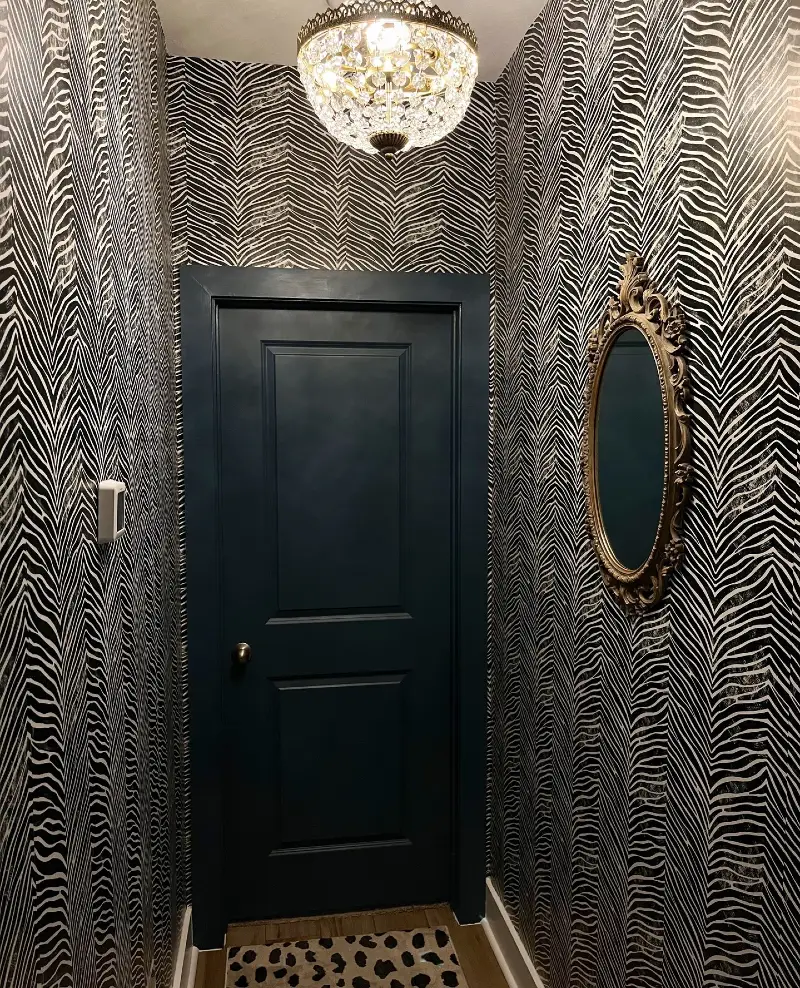 10. Zebra Stripe Hallway with Crystal Chandelier and Ornate Gold Mirror Accent
