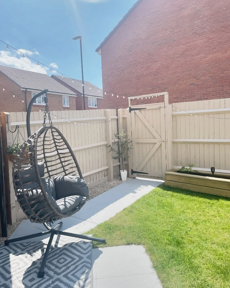 11. Cream Fence Gate with String Lights, Egg Chair, and Raised Planter