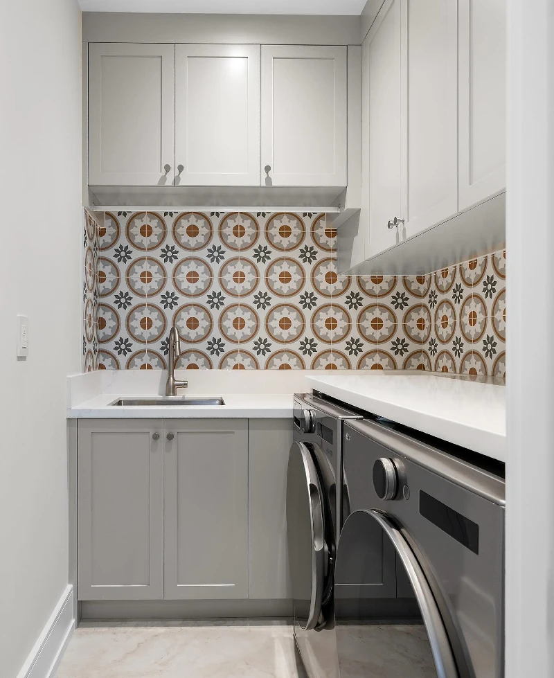 12. Gray Galley Laundry Room with Patterned Tile Backsplash, Upper Cabinets, and Sink Counter