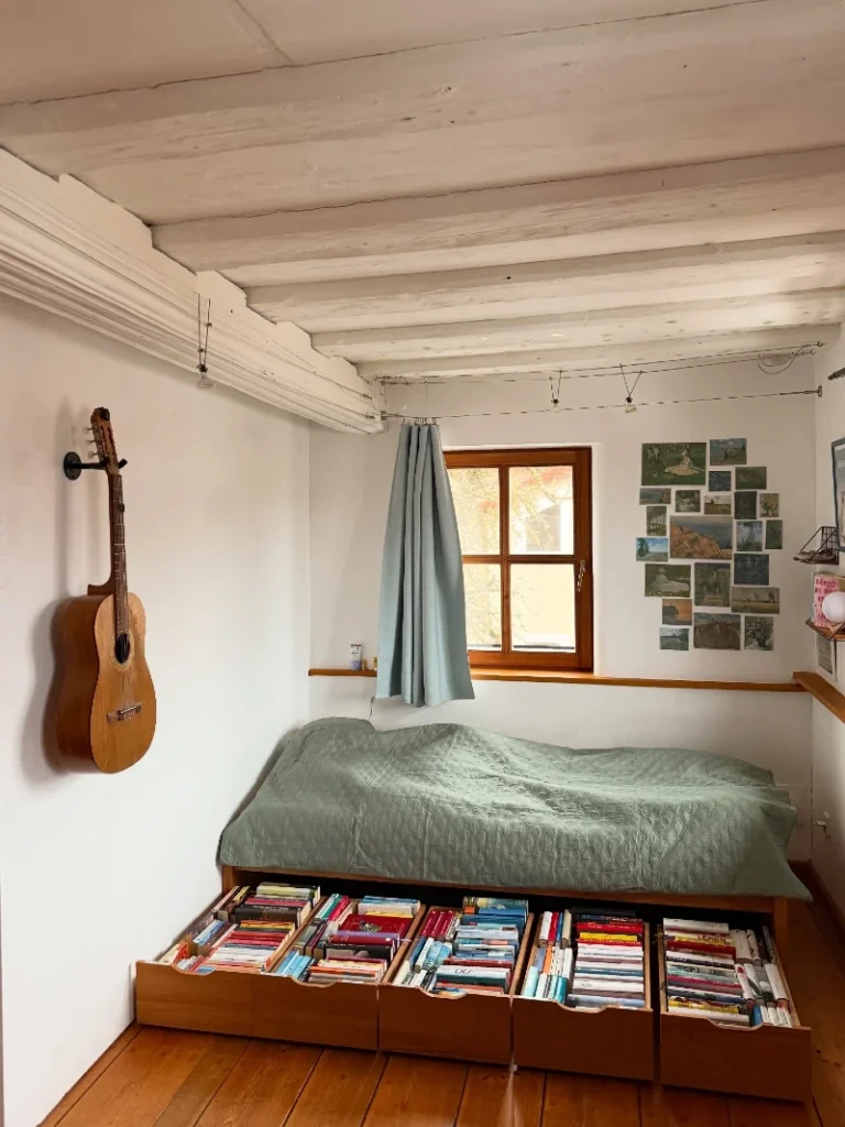 12. Low Wood Bed with Pullout Book Drawers, Sage Quilt, and Wall-Hung Guitar