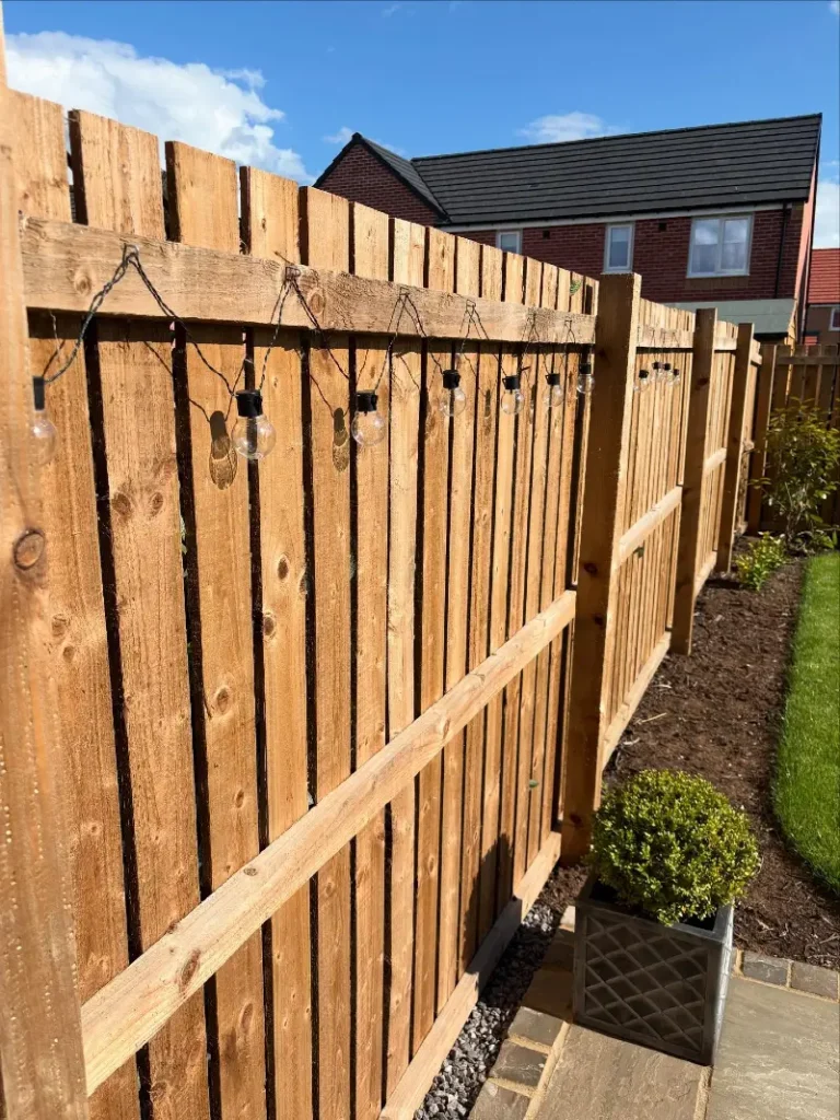 12. Natural Timber Fence with Globe String Lights and Boxwood Planter