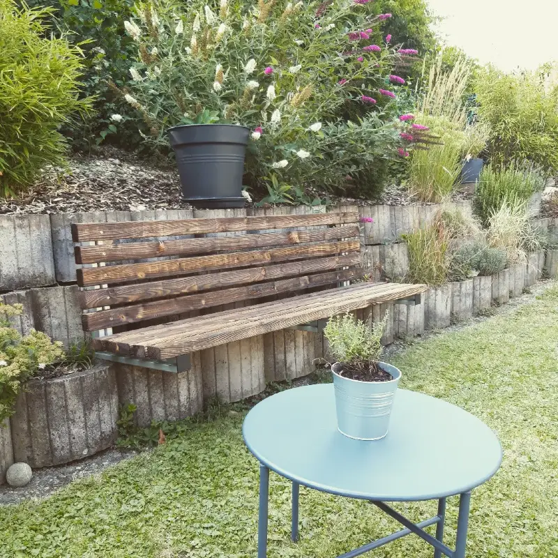 12. Slatted Wood Garden Bench Mounted on a Concrete Retaining Wall