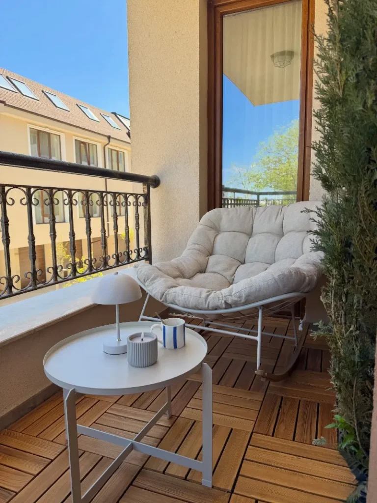 12. Warm Wood Tile Balcony with Cushioned Saucer Chair, White Tray Table, and Tall Cypress Screen