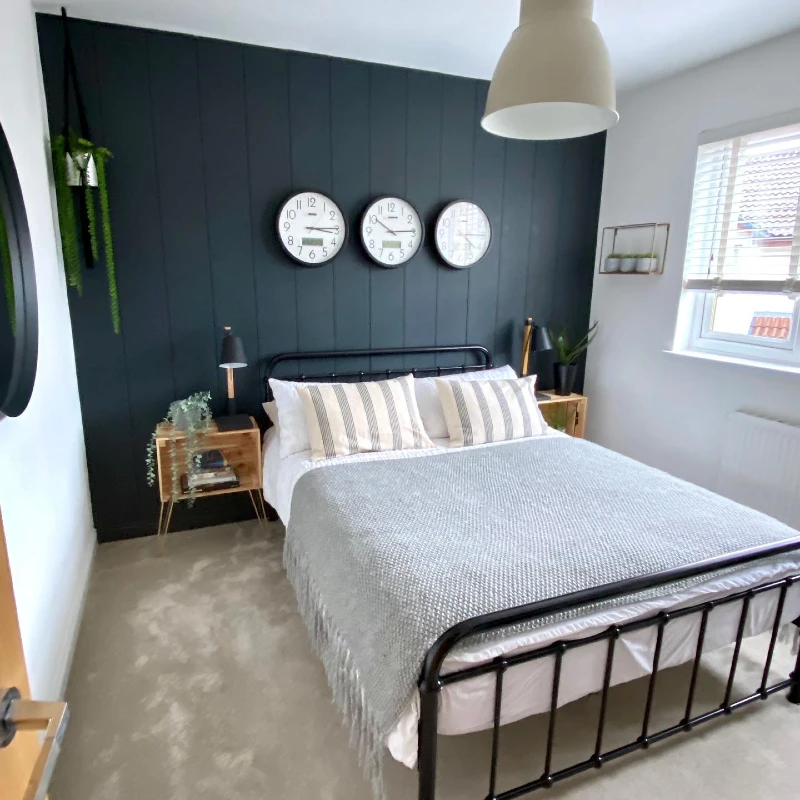 13. Dark Green Panel Wall with Black Metal Bed and Twin Clock Display