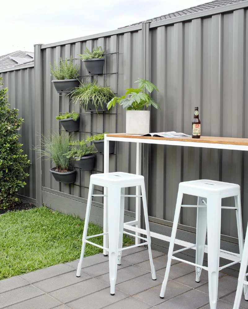 13. Grey Metal Fence with Vertical Herb Planters and White Bar Stools