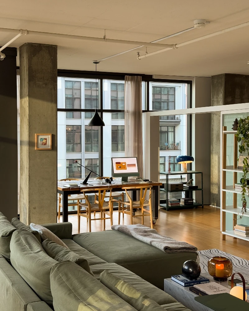 13. Olive Sectional Loft with Concrete Columns, Long Work Table, and Warm Window Light