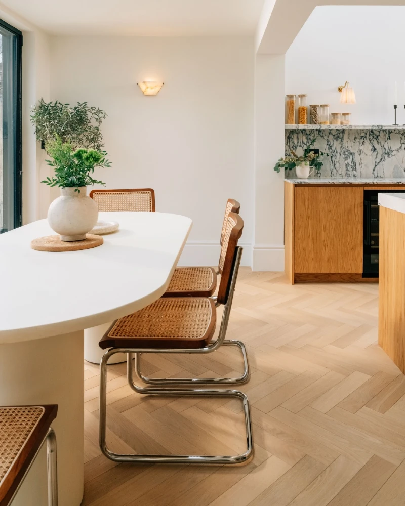 13. Pale Herringbone Dining Floor with Cane Chairs and Marble Kitchen Backsplash