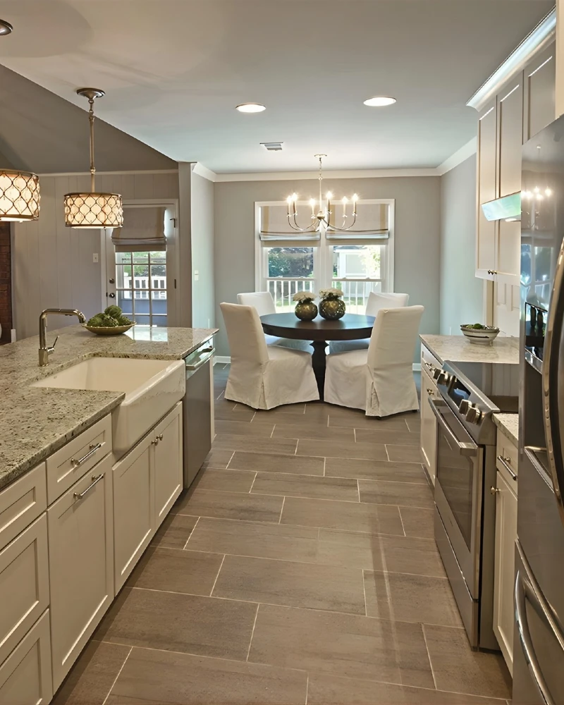 13. White Galley Kitchen with Granite Counters, Farmhouse Sink, and Round Dining Table Beyond