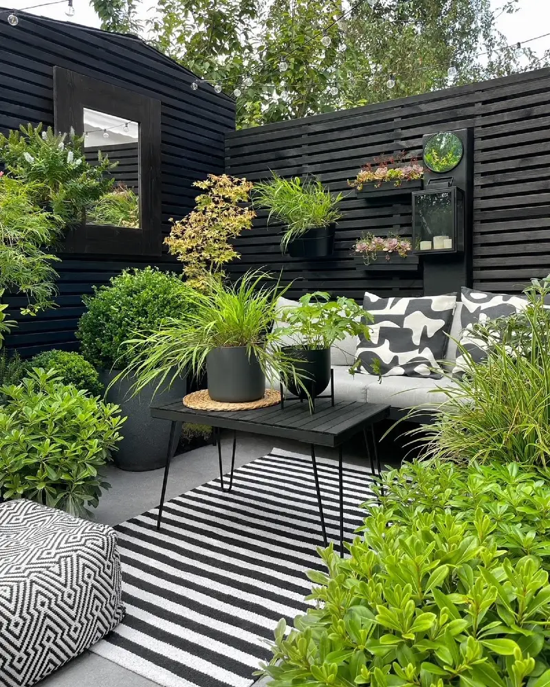 14. Black Slatted Fence Lounge with Mirror, Lantern Shelf, and Striped Rug