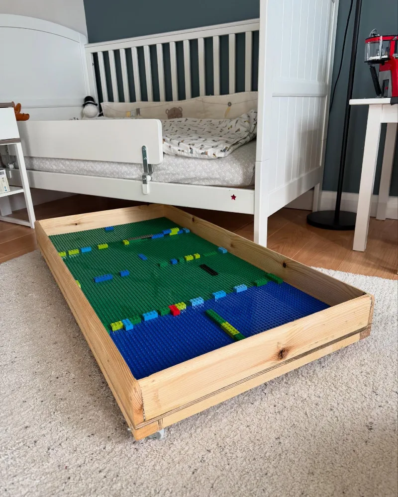 14. Rolling Lego Tray Beneath a White Bed with Raw Wood Frame