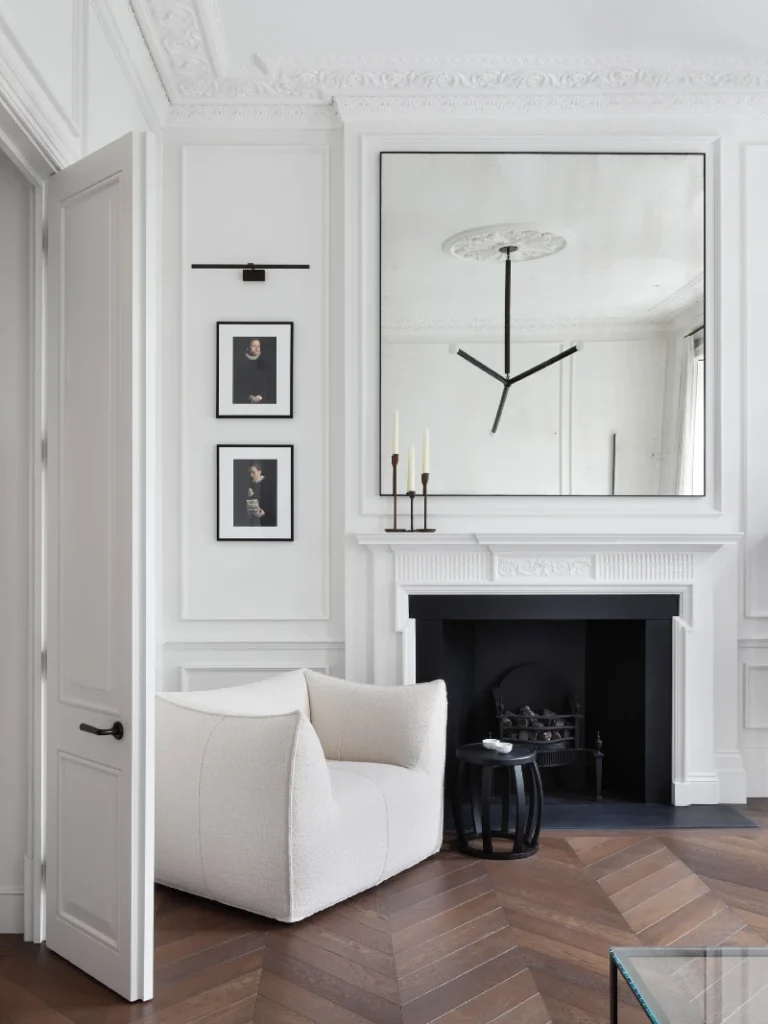 14. White Fireplace Wall with Oversized Mirror, Cream Bouclé Chair, and Black Accent Table