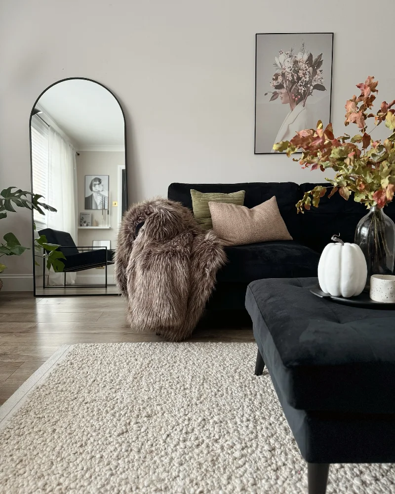 15. Arched Floor Mirror with Black Sofa, Plush Rug, and White Pumpkin Tray