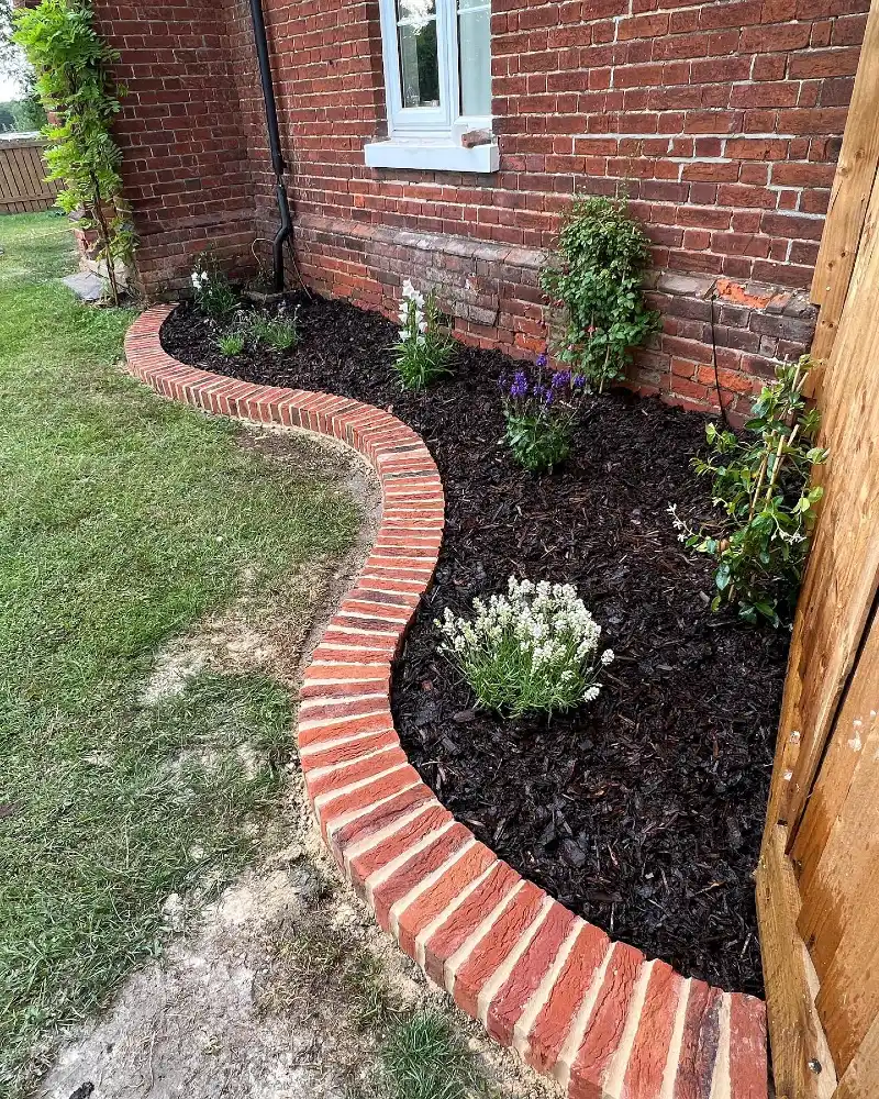 15. Curved Brick Edging with Dark Mulch, Lavender, and Climbing Greenery