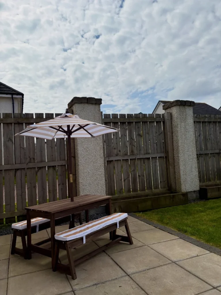 15. Dark Wood Patio Benches with Striped Umbrella and Matching Seat Pads