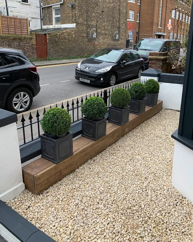 16. Gravel Courtyard with Black Planters, Boxwood Balls, and a Timber Ledge