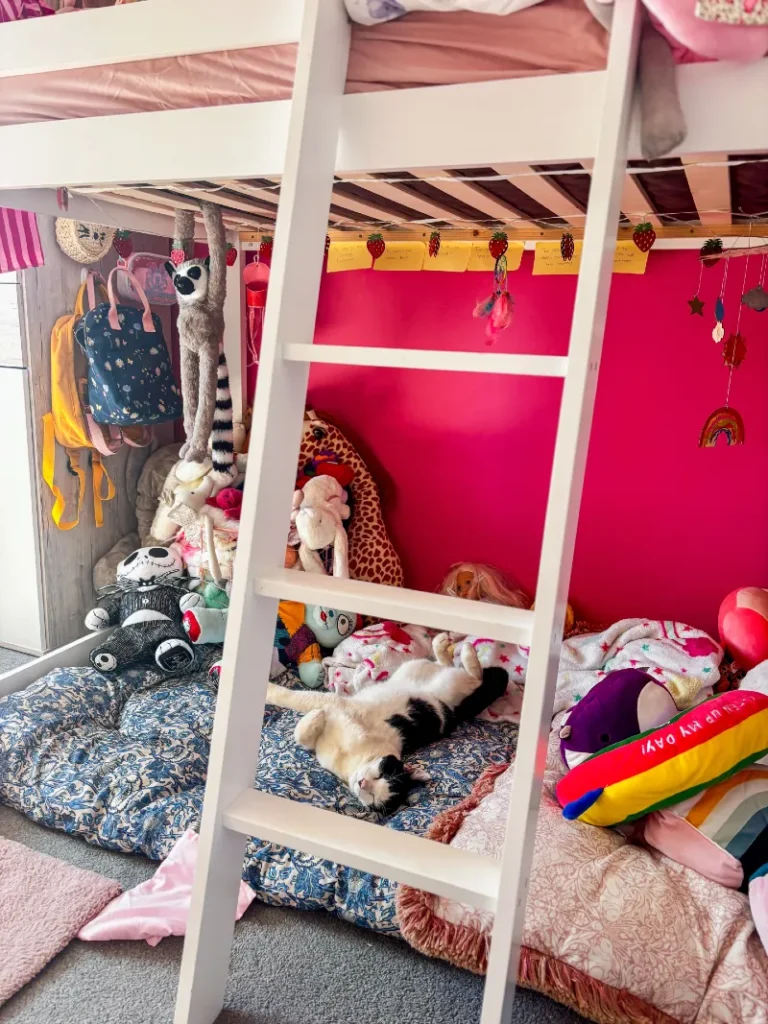 16. Loft Bed Hideaway with Pink Wall, Floor Cushions, and Hanging Strawberry Garland