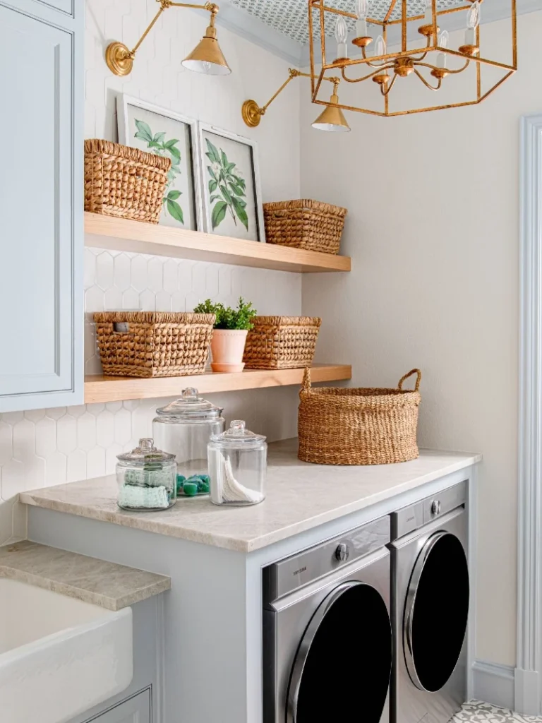 16. Pale Blue Laundry Room with Woven Baskets, Brass Lights, and Floating Wood Shelves