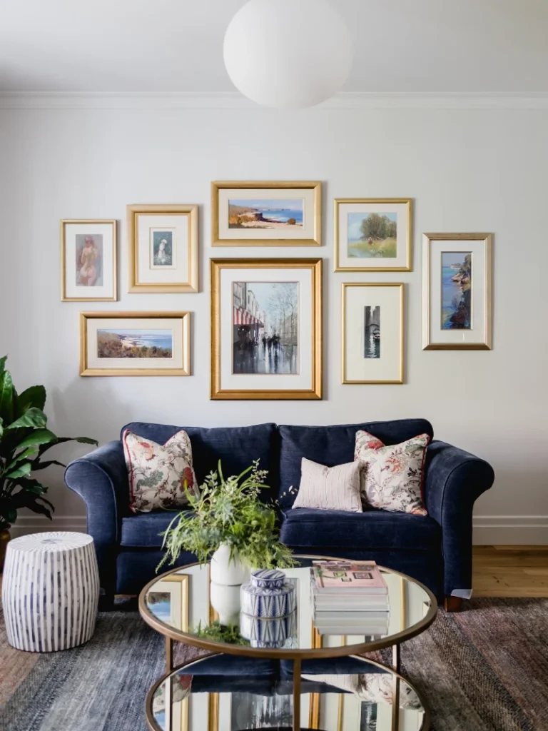 17. Gold Framed Coastal Gallery Wall Above Navy Sofa with Balanced Symmetry