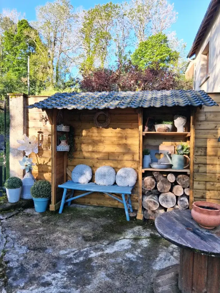 18. Blue Painted Bench Under Corrugated Roof with Log Storage Shelves