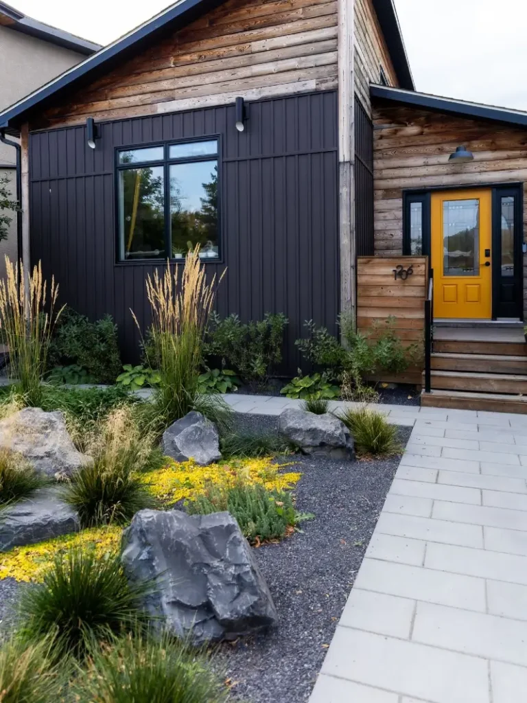 18. Charcoal Siding Front Garden with Boulder Gravel Beds, Tall Grasses, and a Yellow Door