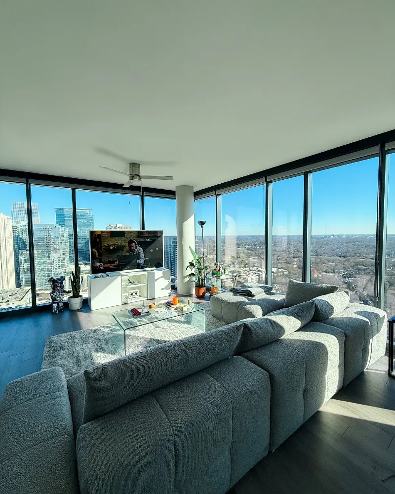 19. Corner High Rise Living Room with Gray Sectional, Glass Table, and City Views