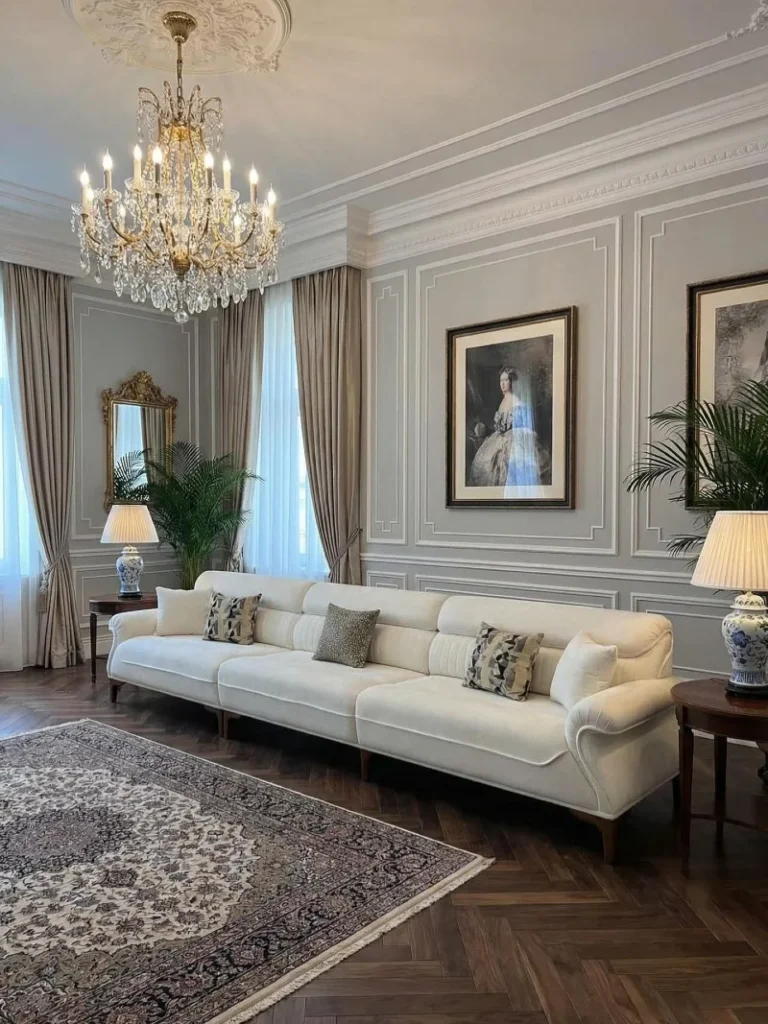 19. Gray Paneled Living Room with Crystal Chandelier, Cream Sofa, and Blue Ceramic Lamps