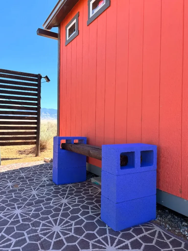 2. Cobalt Cinder Block Bench with Dark Timber Beam Against Red Siding