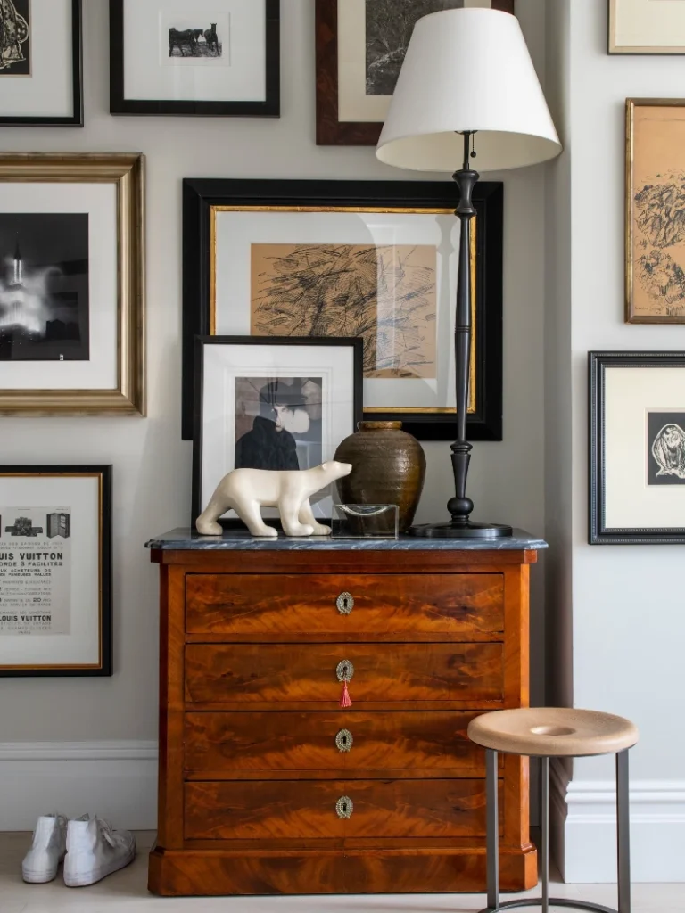 2. Layered Black Frame Gallery Above Wood Dresser with Mixed Art and Sculpture Accents