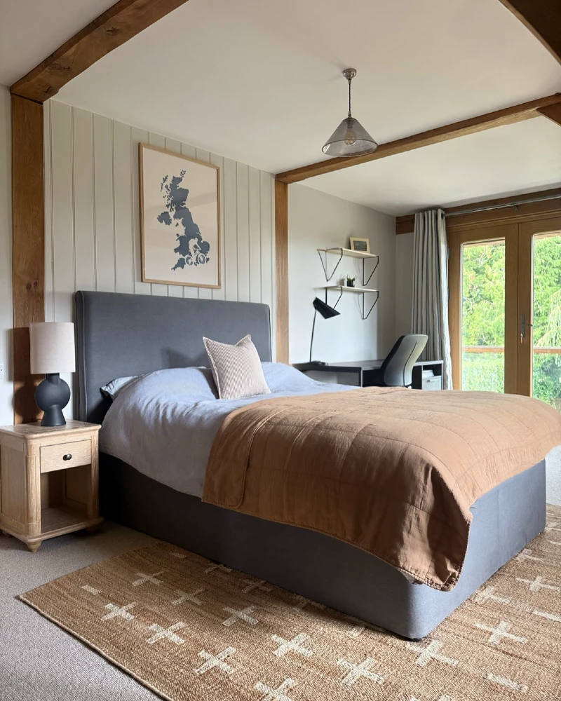 21. Gray Upholstered Bed with Tan Quilt, Wood Beams, and Built-In Desk Corner