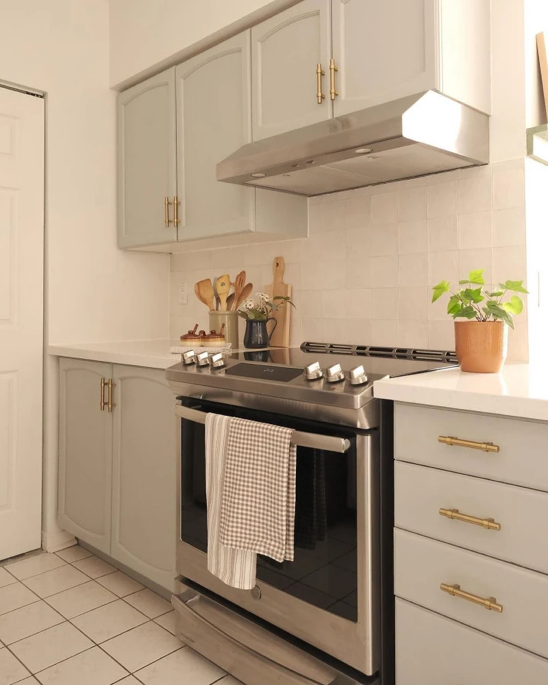 21. Soft Sage Cabinets with Brass Hardware and Stainless Stove Contrast