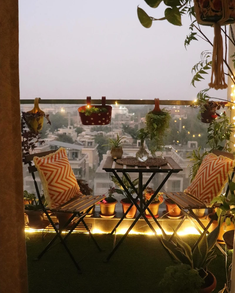 3. Bistro Balcony with Orange Chevron Pillows, Rail Planters, and Golden String Lights
