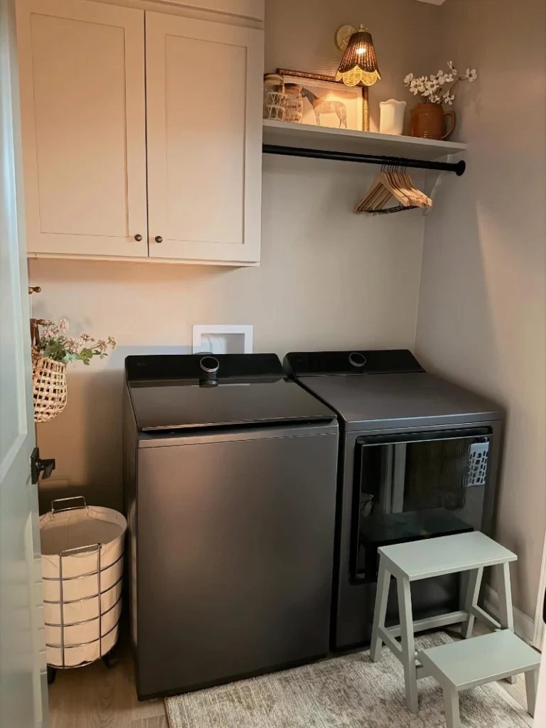 3. Taupe Laundry Nook with Shaker Cabinet, Black Hanging Rod, and Warm Sconce