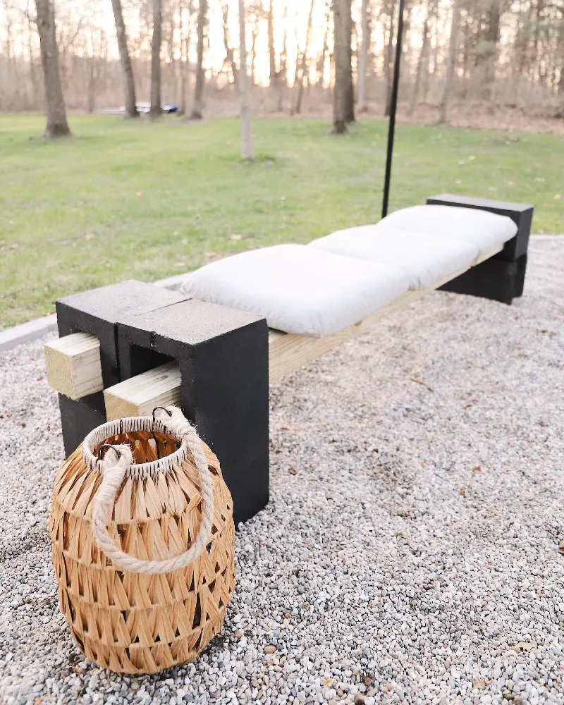 4. Black Cinder Block Lounge Bench with Cream Cushion on Gravel Patio