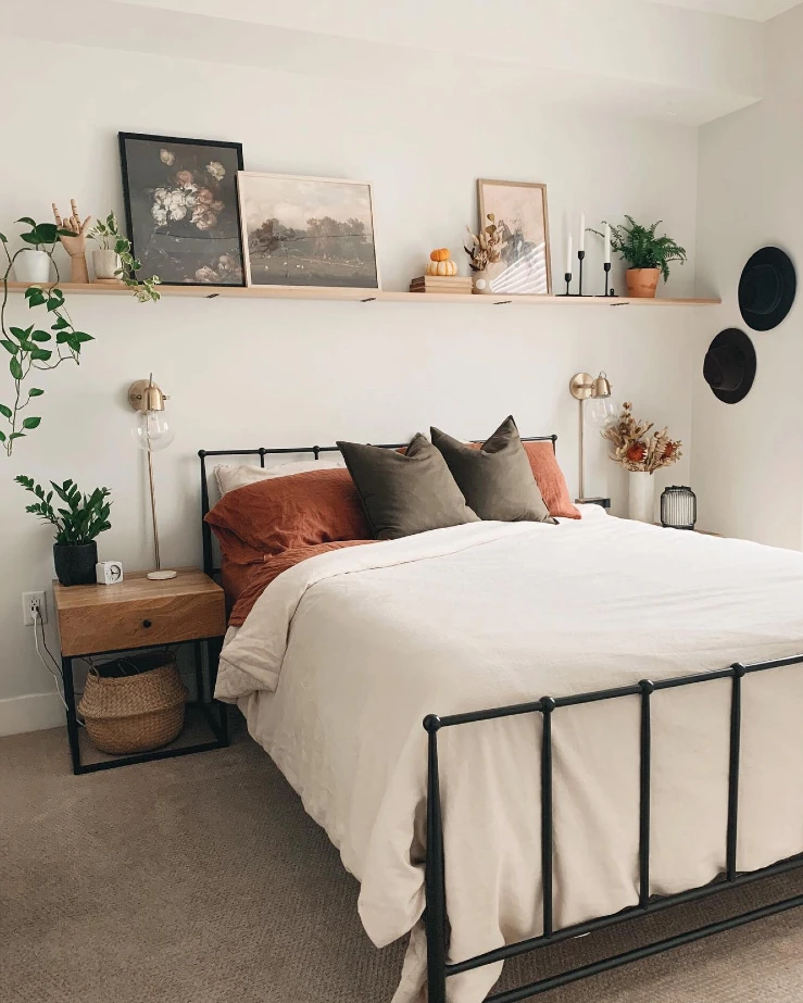 4. Long Bedroom Shelf with Leaning Art, Trailing Plants, and Black Candlesticks