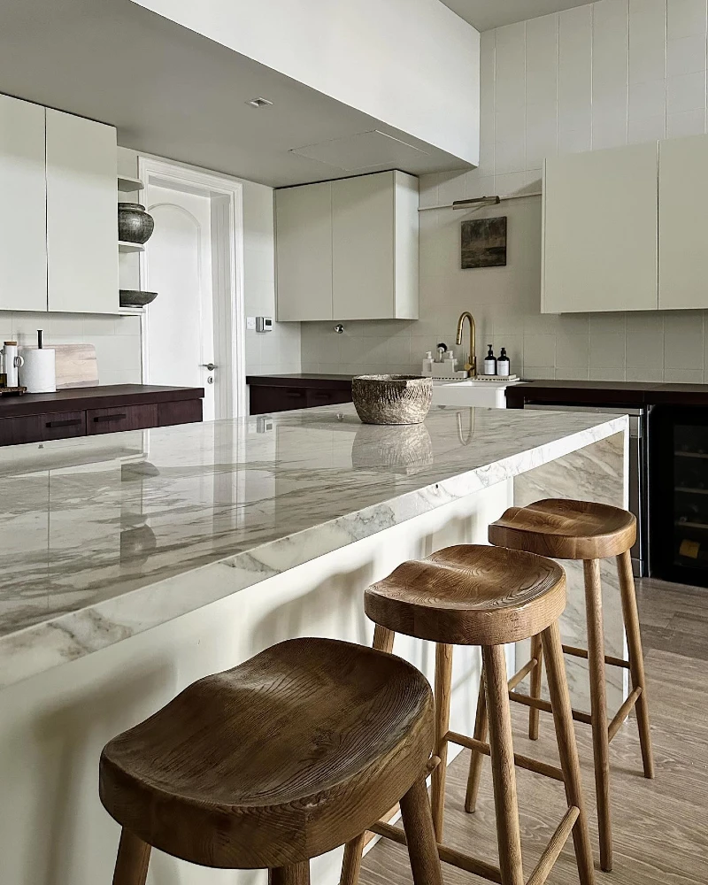 4. Marble Waterfall Island with Wood Stools and Soft Neutral Cabinets