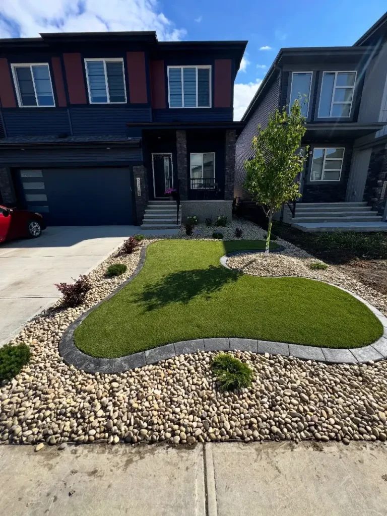 5. Curved Artificial Turf Lawn with River Rock Borders and a Young Front Yard Tree