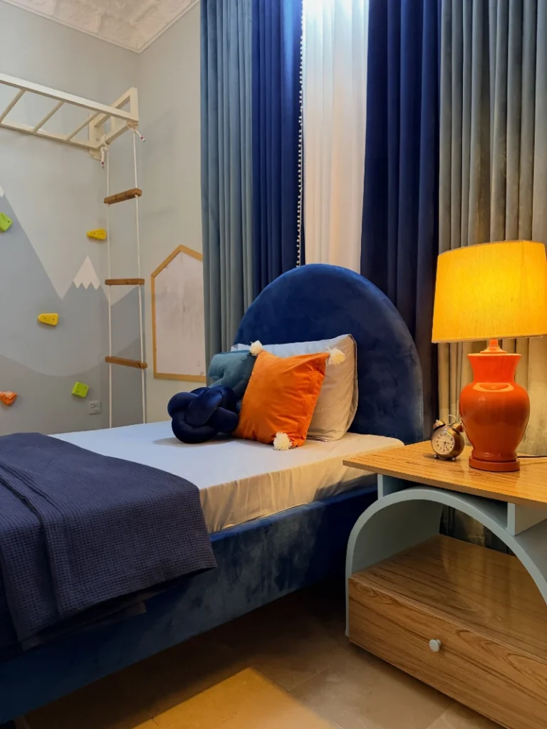 5. Navy Velvet Bed with Orange Lamp, Rope Ladder, and Climbing Wall