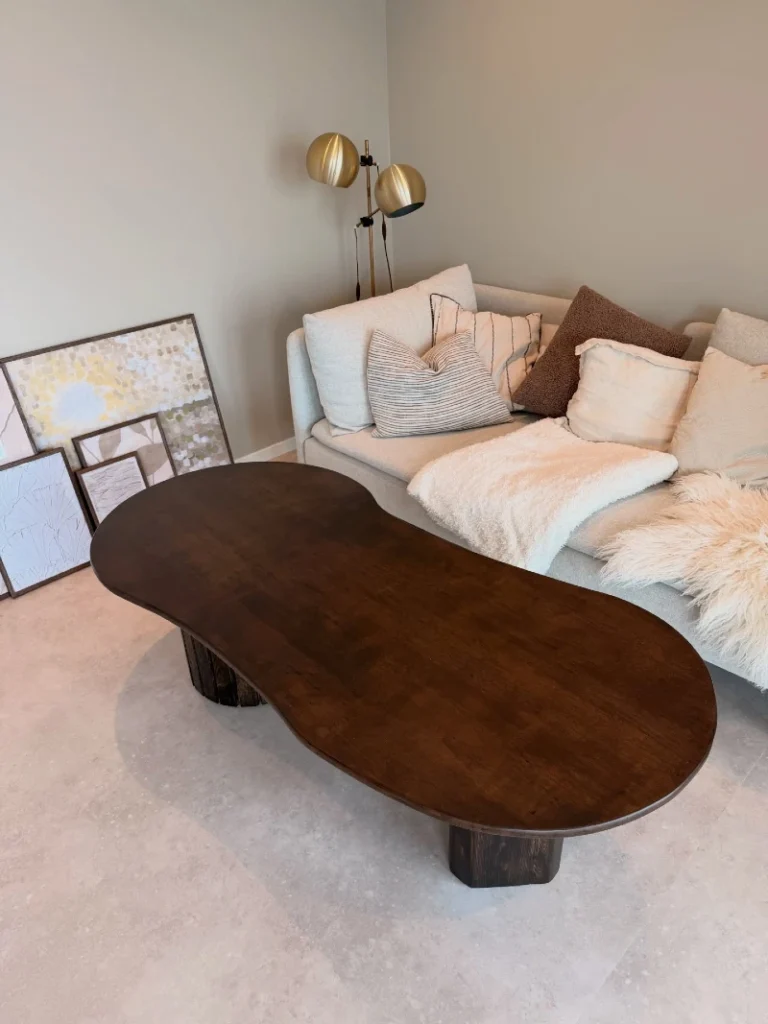 5. Oversized Bean Shaped Dark Wood Coffee Table with Cream Sofa and Layered Pillows