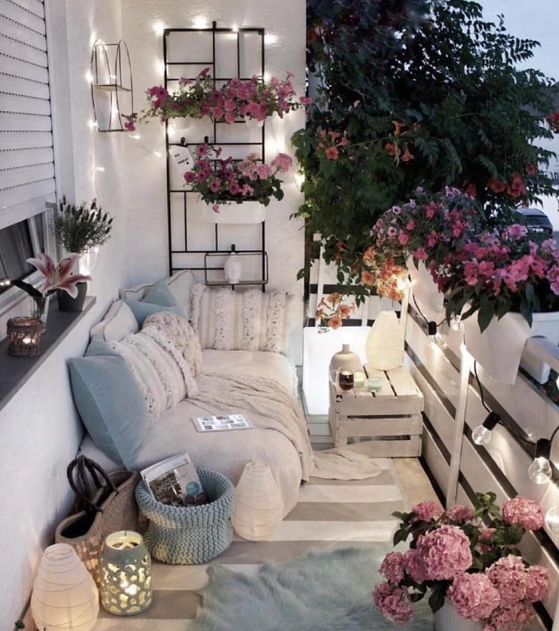 5. White Balcony Lounge with Pink Flowers, Soft Blankets, and Warm Rail Lights