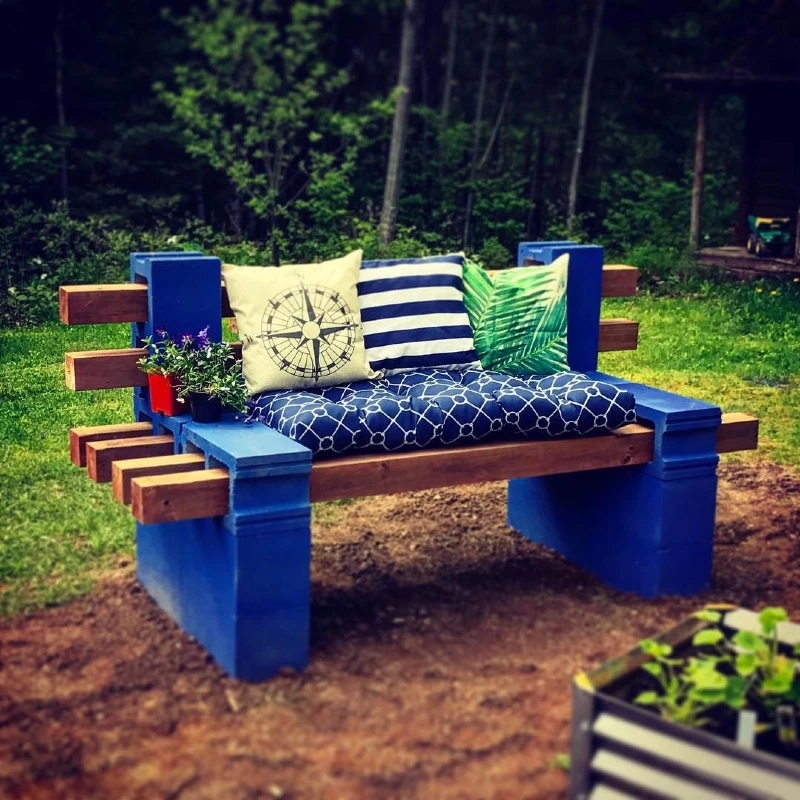 6. Blue Cinder Block Garden Bench with Striped Cushions and Planter Armrest