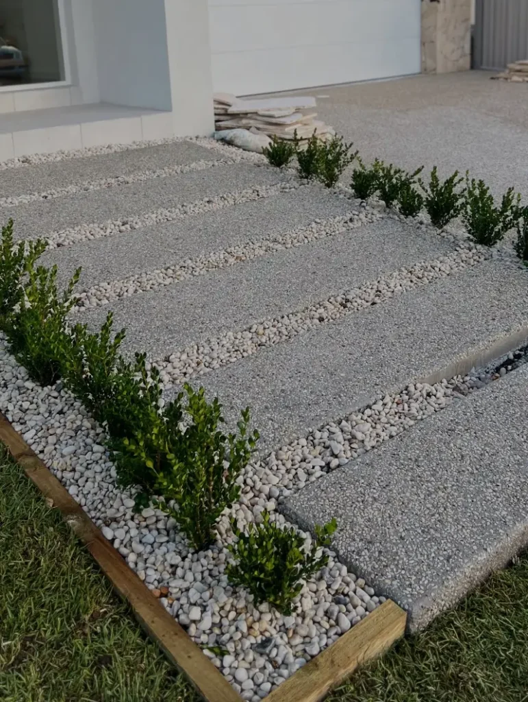 6. Concrete Slab Walkway with White Pebble Gaps and Boxwood Rows
