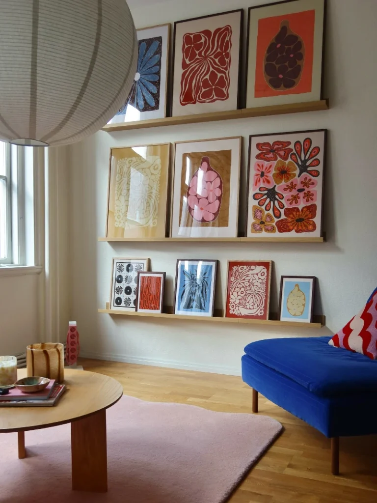 6. Floating Wooden Ledge Gallery Wall with Bold Botanical and Graphic Prints Above Blue Seating