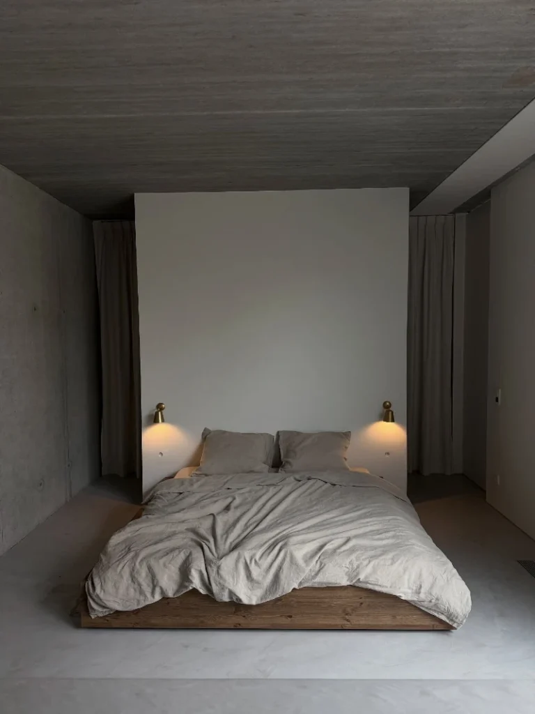 6. Low Wood Platform Bed with Concrete Walls and Brass Wall Sconces