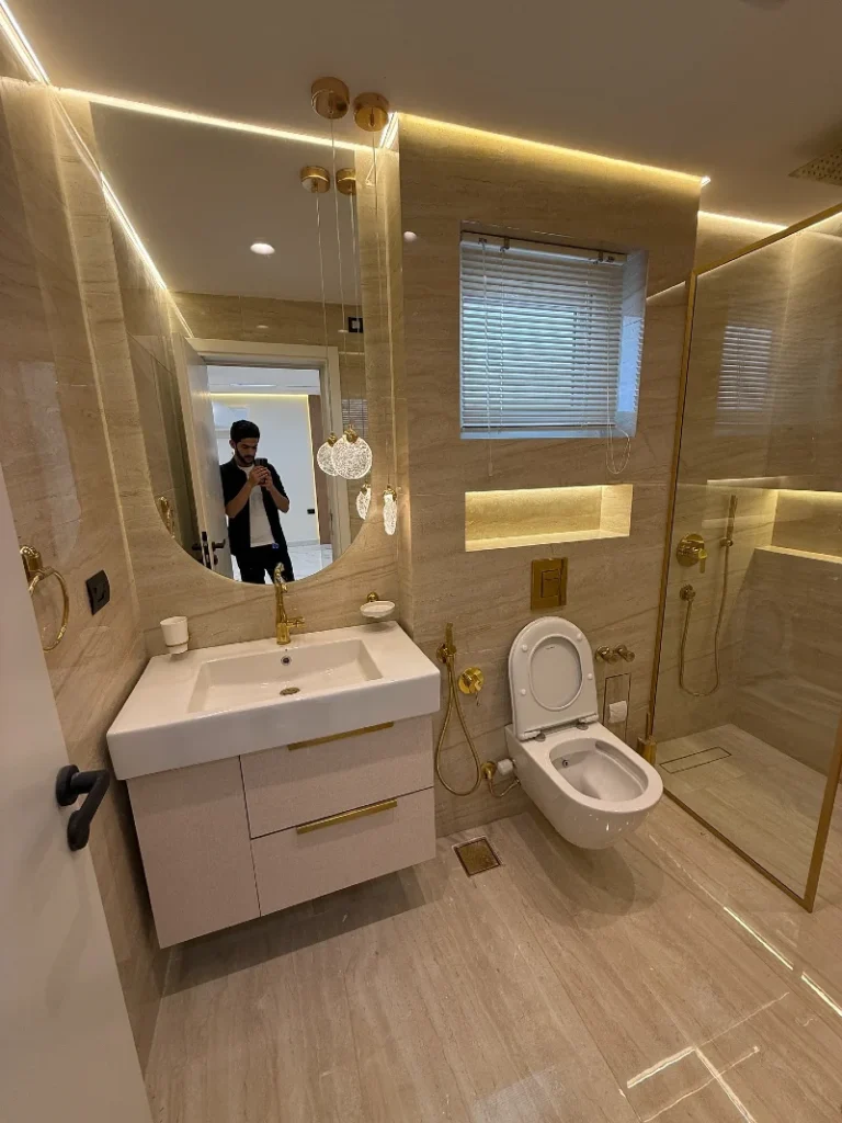7. Beige Stone Bathroom with Gold Glass Shower Frame