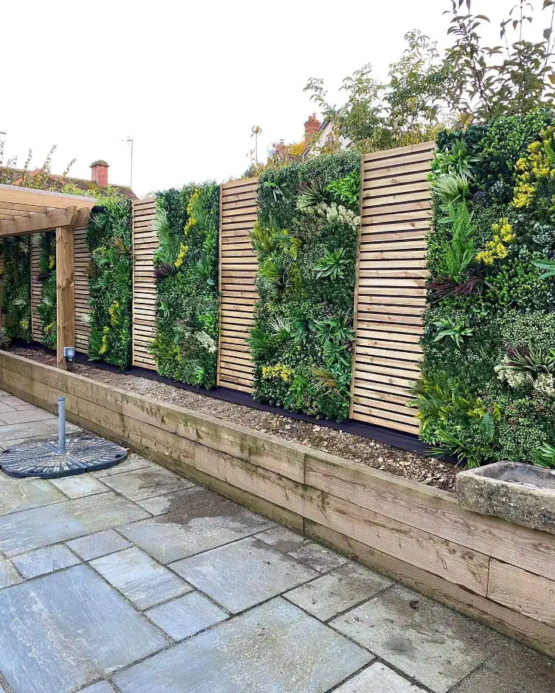 7. Slatted Wood Fence with Lush Green Wall Panels and Raised Timber Border