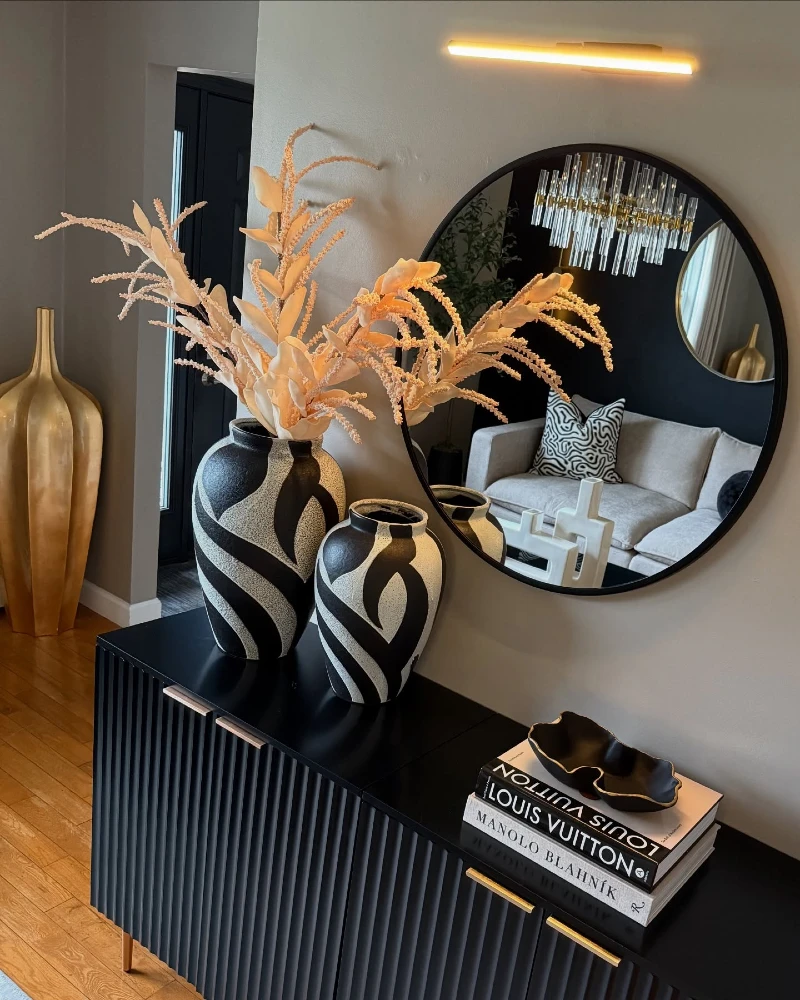 8. Black Fluted Sideboard with Round Mirror and Patterned Ceramic Vases